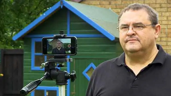 An image of me filming myself using the Filmic Pro video app on an iPhone SE. Clearly, I cannot see the phone's display since I'm using the higher quality rear facing camera. This makes framing myself a problem. Filmic Remote offers a solution, since it can mirror the display of my iPhone and allow remote control of Filmic Pro.
