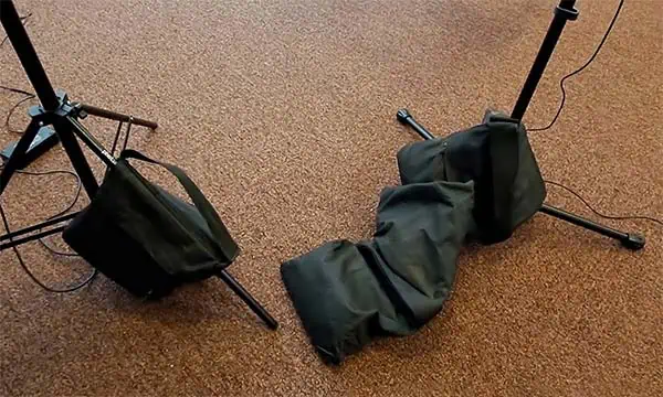 Sandbags holding down feet of a light stand and mic stand
